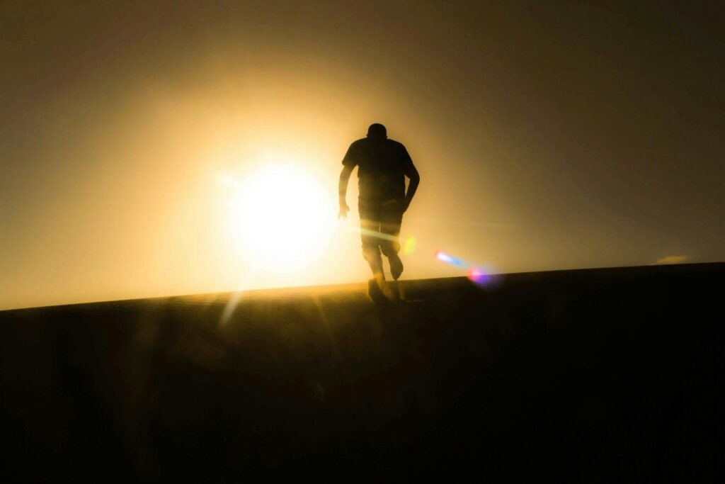 pexels-photo-325790-325790 Silhouette of a man running uphill against a bright desert sunrise, capturing a sense of solitude and determination.