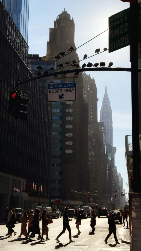 Pedestrians crossing in NYC with Chrysler Building in view. Urban commute scene.